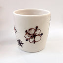 White ceramic cup with black floral designs on a white background
