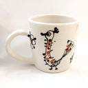 White mug with black and orange abstract design on a white background