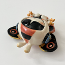 Ceramic sculpture of a small character with a large head wearing a Mothra costume, with a hood hat and a large set of wings behind it matching Mothra's colorways.