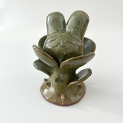 Small ceramic sculpture of a plant with leaves and a thorny base. Coming out the top is a bunny's head.
