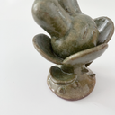 Small ceramic sculpture of a plant with leaves and a thorny base. Coming out the top is a bunny's head.