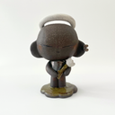 Dark brown ceramic sculpture of a character with a very large head and a small body. It has earring cuffs, a halo, and holds a small white flower.