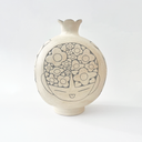 Cream colored ceramic vase with a very round body and a small fluted top, almost resembling a pomegranate in shape. On the front is a design of a person's head with floral patterned hair.