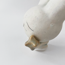 Small white ceramic sculpture of a bunny character with a calm, closed eye expression. It has a large head and a tiny body, holding a star.