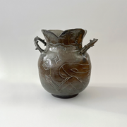 Glossy ceramic vase, with a carved design of a girl holding out her hands with a small bunny planet floating above it. The handles of the vase have thorns.
