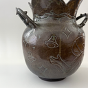 Glossy ceramic vase, with a carved design of a girl holding out her hands with a small bunny planet floating above it. The handles of the vase have thorns.