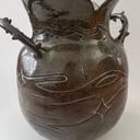 Glossy ceramic vase, with a carved design of a girl holding out her hands with a small bunny planet floating above it. The handles of the vase have thorns.