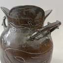 Glossy ceramic vase, with a carved design of a girl holding out her hands with a small bunny planet floating above it. The handles of the vase have thorns.