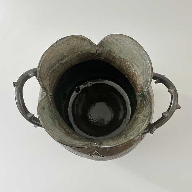 Glossy ceramic vase, with a carved design of a girl holding out her hands with a small bunny planet floating above it. The handles of the vase have thorns.