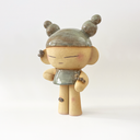 Ceramic statue of a character with closed eyes, a small dress, ear cuffs and their hair up in space-like buns. On their arm is a small caterpillar and on their knee is a bandaid. 