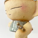 Close up of a ceramic sculpture of a character with a tiny caterpillar on its arm.