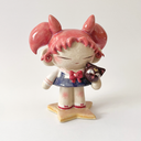 Ceramic figure of a girl with pink, anime-like hair, a sailor outfit and holding a cute black cat head. She stands on a star shaped base.