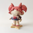 Ceramic figure of a girl with pink, anime-like hair, a sailor outfit and holding a cute black cat head. She stands on a star shaped base.