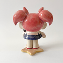 Ceramic figure of a girl with pink, anime-like hair, a sailor outfit and holding a cute black cat head. She stands on a star shaped base.