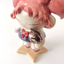 Ceramic figure of a girl with pink, anime-like hair, a sailor outfit and holding a cute black cat head. She stands on a star shaped base.