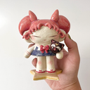 Ceramic figure of a girl with pink, anime-like hair, a sailor outfit and holding a cute black cat head. She stands on a star shaped base.