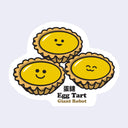 Die cut sticker of 3 egg tarts with glossy surfaces, each has a different expression cute cartoon face. Below is text that reads "Egg tart" in chinese hanzi and then in english followed by "Giant Robot"