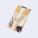 Folded tea towel with paper sleeve.