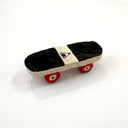 A miniature hand-painted ceramic skateboard with a black and white deck, red wheels, and a small onigiri logo on the center, set against a plain white background.