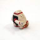 A small hand-painted ceramic figurine of a character resembling an onigiri, wearing red sweatband, and black and red basketball sneakers, holding an orange basketball and pointing, set against a plain white background.