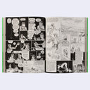 Open comic book with black and white illustrations on a white background