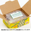 Open cardboard box with bubble wrap and a green invoice inside, featuring a pineapple-themed label.