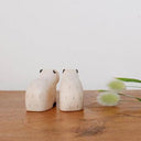 Two wooden capybara figurines on a wooden surface with a white background