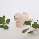 Wooden figurine of a fluffy chow chow dog, standing with its mouth open in a smile.