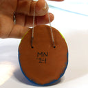 Backside of hanging sculpture, with a clay backing and the artist's signature.