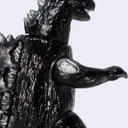 A glossy black Godzilla toy figure with silver claws and feet, standing on a light gray background.