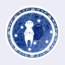 White ceramic round plate with a floral design as the border and a main circular design of a white cartoon-like character laying on a bed of flowers alongside a dark blue blob character.