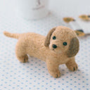 Small brown dog felted sculpture on a blue polka dot surface