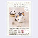 Packaging for a needle felting kit to make a calico cat, sitting with its arms and legs under it.