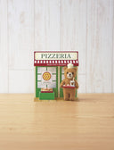 Needle felting kit of a bear with a small chef's hat, standing outside of a pizza restaurant with a tray of pizza.