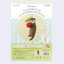 Packaging for a needle felting kit of an other holding a cherry, attached to a keychain.