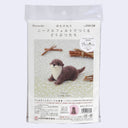 Packaging for a needle felting kit of a small brown otter, laying on its stomach with its head raises and a cute expression.