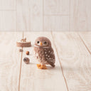 Small needle felting of an owl, brown with white spots and a yellow beak and talons.