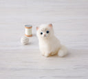 Needle felting of a Persian cat, white a fluffy sitting with a happy, curious expression.