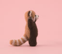 Side view of a red panda needle felting, with its tail behind it and its arms raised.