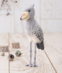 Needle felted sculpture of a shoebill bird, gray, white and dark gray with a yellow beak.