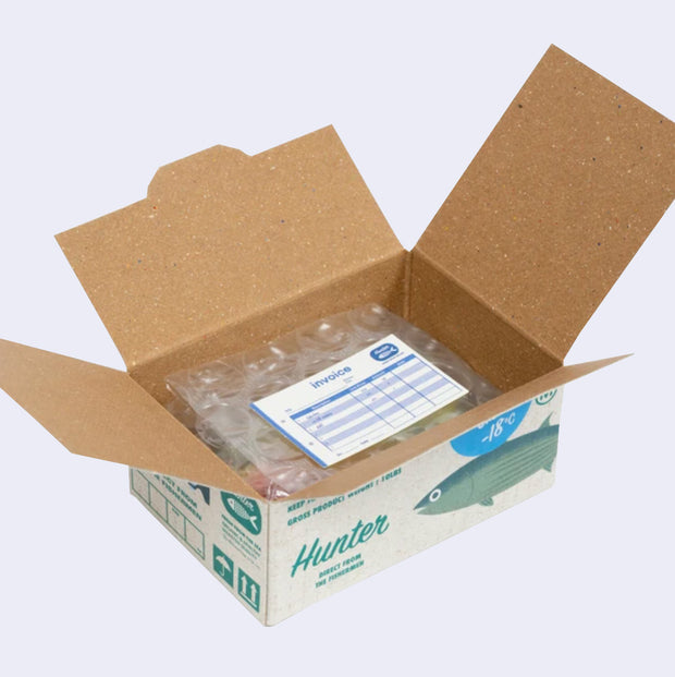  Open box of miniature stickers, made to resemble a shipping box with bubble wrap around the product and a small invoice. Exterior of box looks like realistic frozen fish packaging.