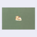 Back view of green birthday card, with a tiny illustration of a hedgehog eating a cupcake.