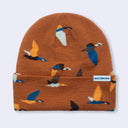 A knit beanie in rust orange with a repeating pattern of stylized birds in blue, yellow, white, and black. A small white brand tag on the cuff reads Bird Collective.