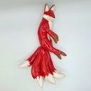 A glossy ceramic fox figurine with 4 tails, in a side profile, featuring a vibrant red body with white accents on its chest, paws, and tail tips, and brown accents on its ears and paws, set against a plain light gray background.