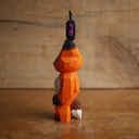 Painted whittled wooden sculpture of a fox with a surprised look on its face. It stands on its hind legs with its hand together. Atop its head is a small butterfly.