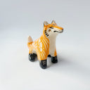 Glossy ceramic sculpture of an orange fox, with carved out poppy flower design on its back and gold colored detailing on its paws and cheeks.