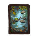 A semi-3D clay artwork, shaped like a card depicting a whimsical forest stream scene with a green frog resting on a rock, surrounded by brown branches, green leaves, and blue-green water, set against a plain white background. Scene is kept within a clay frame made to look like wood.