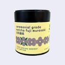 Ceremonial grade matcha fuji murasaki container with yellow label and black lid on a light purple background