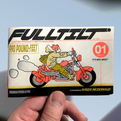 Hand holding a magazine cover with a motorcycle illustration and text.