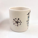 White ceramic cup with black floral patterns on a white background